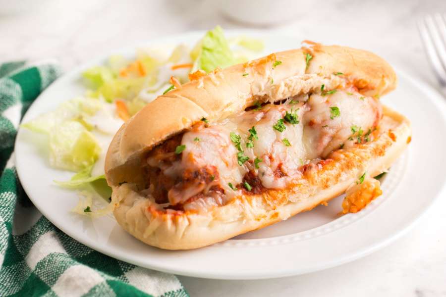 Baked Meatball Sub on a plate with a salad