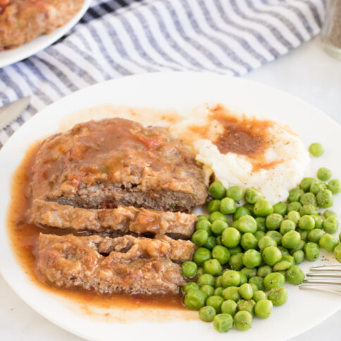 Crockpot Cubed Steak on a plate with peas and potatoes