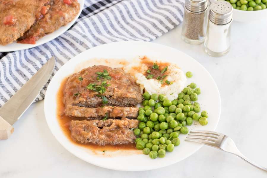 Crockpot Cubed Steak on a plate with peas and potatoes