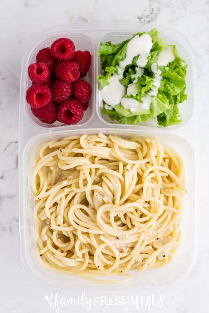 Cacio e Pepe packed in a lunchbox with salad and fruit
