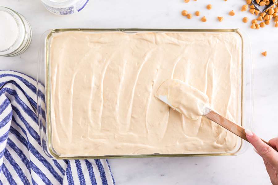 Spreading the peanut butter cheesecake filling evenly over sugar cookie crust