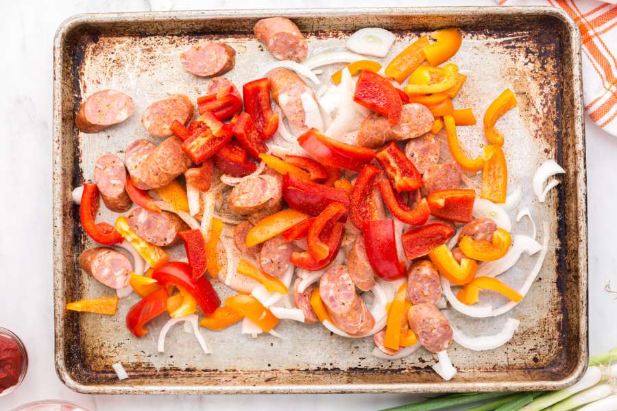 sausage slices, onions and peppers on baking sheet