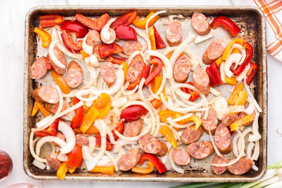 sausage slices, onions and peppers on baking sheet