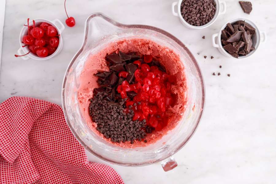 adding chocolate chunks, chips and cherry to the bowl