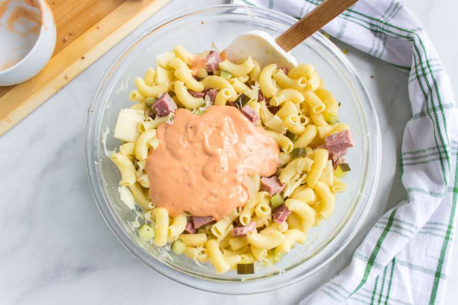 anding dressing and pasta to bowl