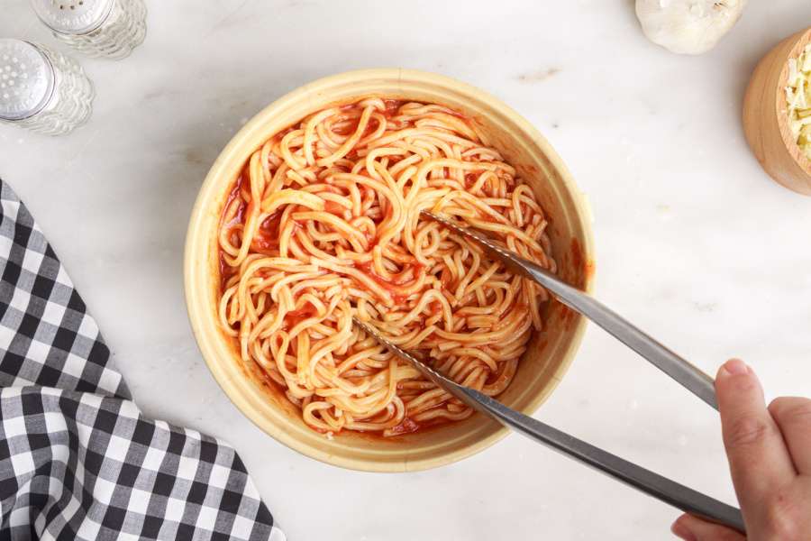 pasta and sauce being mixed in a bowl