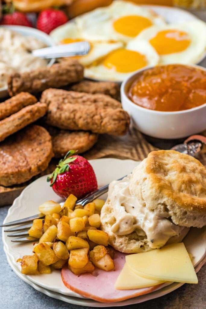 plate with potatoes, biscuit and gravy, cheese and strawberries