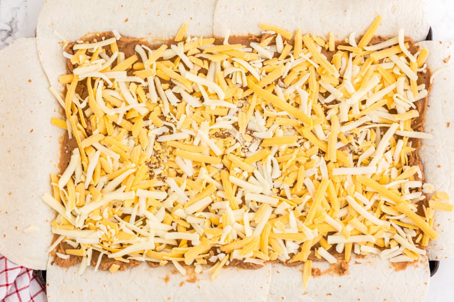 sprinkling shredded cheese on top of beans