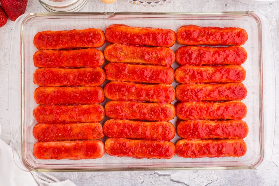 strawberry coated ladyfingers in the bottom of baking dish