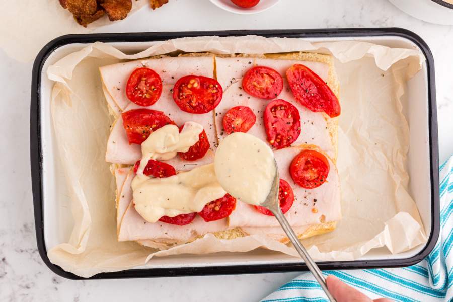 adding sauce on top of tomatoes