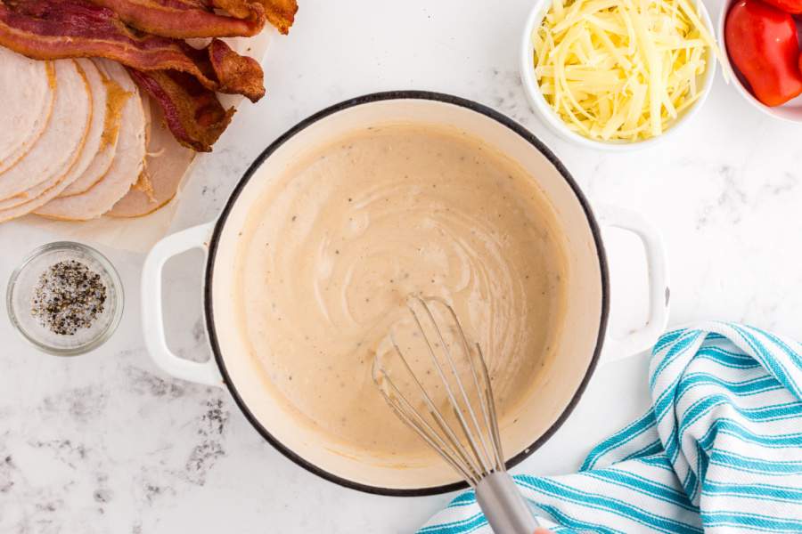 stirring sauce in pot with whisk