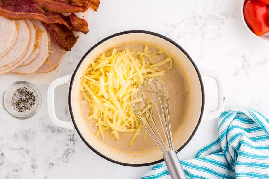 adding grated cheese to pot