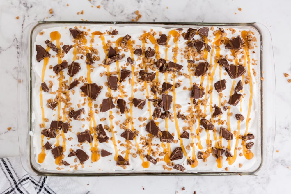 cake topped with candy bar bits and caramel sauce