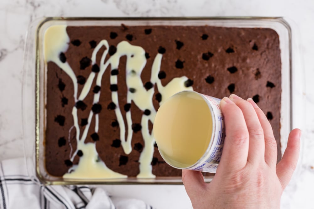 pouring condensed milk over cake