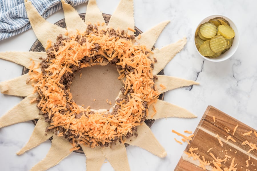 adding shredded cheese to top of ground beef