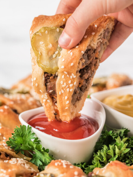 dipping a piece of Cheeseburger Crescent Ring into ketchup