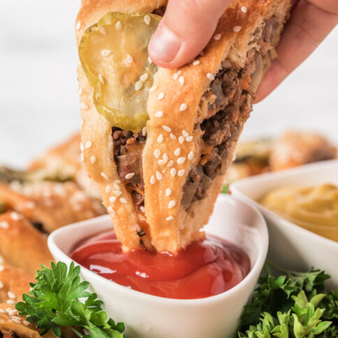 dipping a piece of Cheeseburger Crescent Ring into ketchup