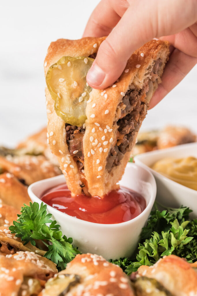 dipping a piece of Cheeseburger Crescent Ring into ketchup 