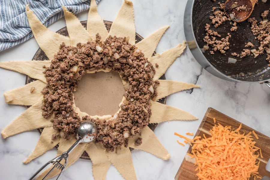 adding beef to the top of crescent rolls dough