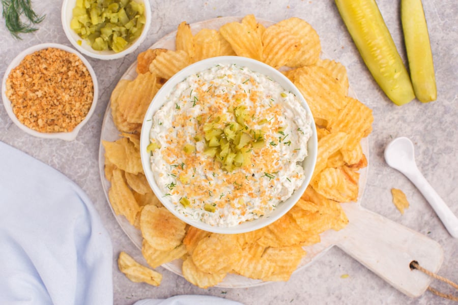 Dill pickle dip in bowl surrounded by chips