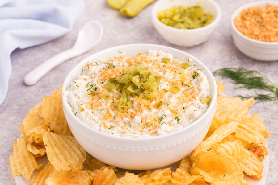 Dill pickle dip in bowl surrounded by chips