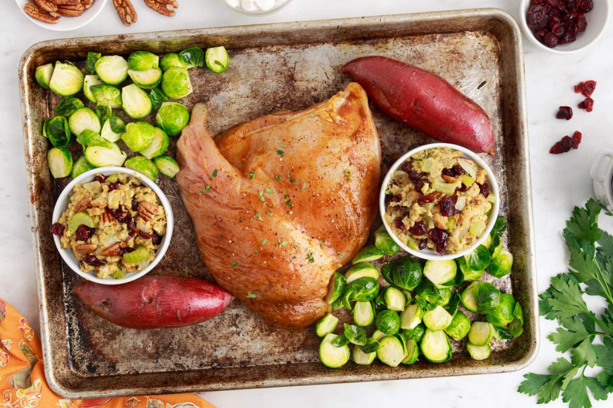 turkey breast, potatoes stuffing cups and brussels sprouts on baking sheet