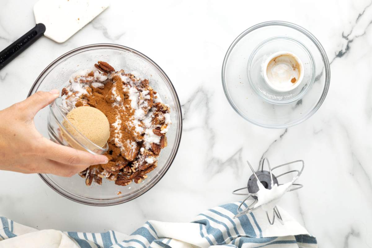 adding nuts and sugars into the bowl with egg whites