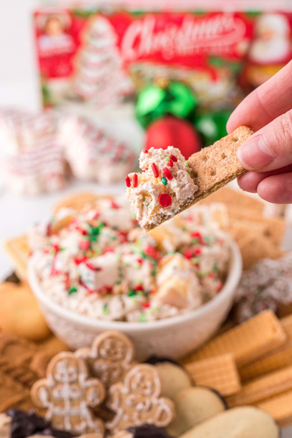 scooping some Little Debbie Christmas Tree Cake Dip with a cookie
