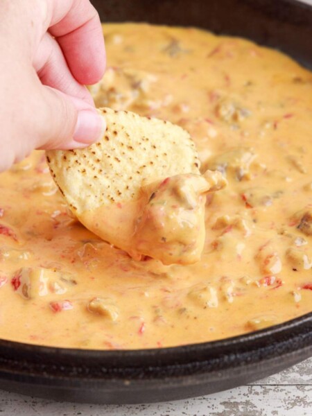 Cheesy Sausage Rotel Dip in a pan with a chip