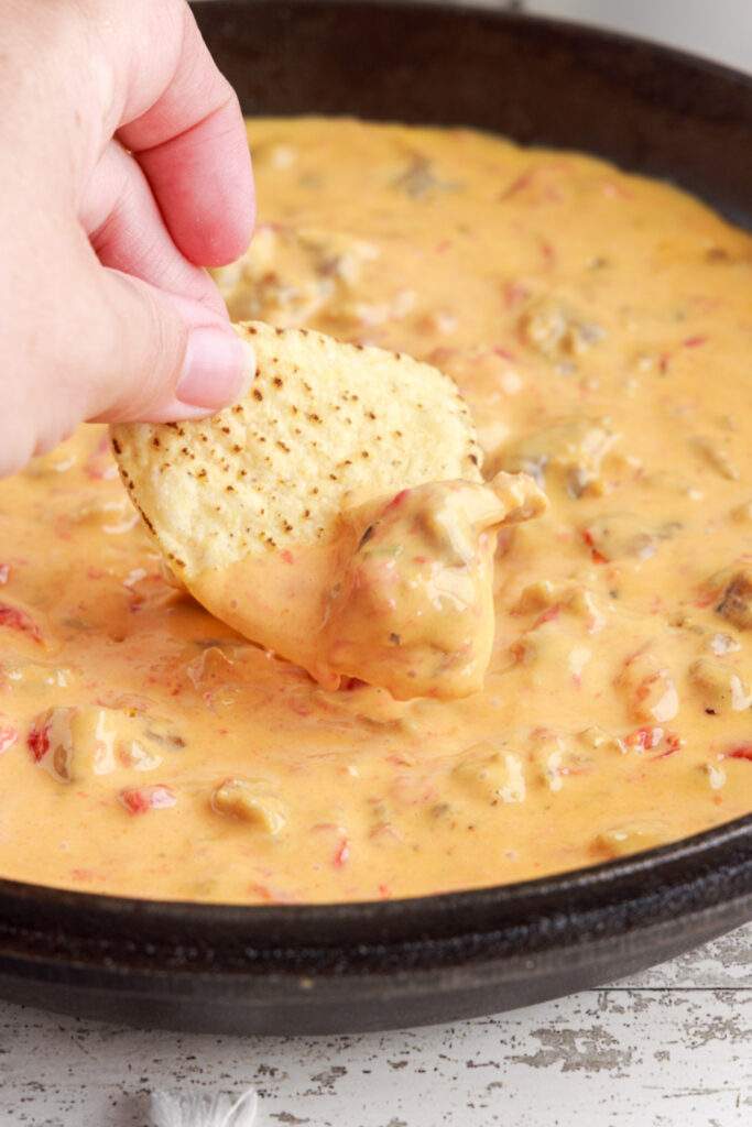 Cheesy Sausage Rotel Dip in a pan with a chip