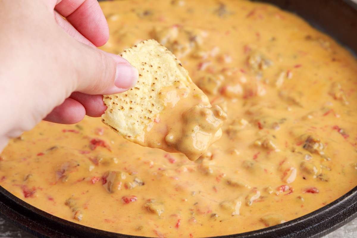 Cheesy Sausage Rotel Dip being scooped up with a chip