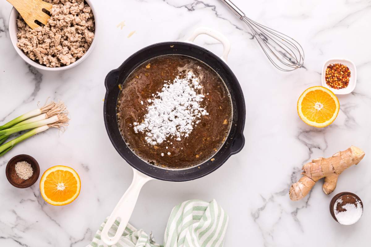 adding corn starch to pan with sauce