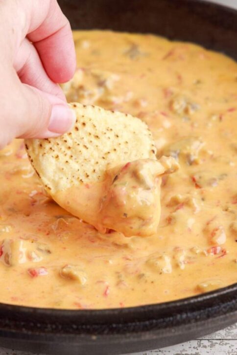 Cheesy Sausage Rotel Dip in a pan with a chip