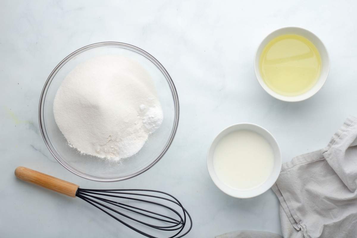 mixing flour, sugar and salt in a bowl, with small bowls of oil and butter milk