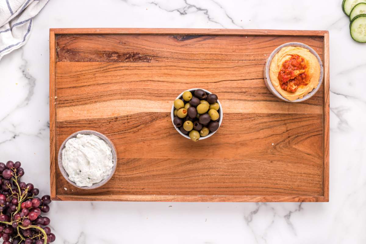 olives and dips in small bowls on board