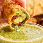 dipping Copycat Cheesecake Factory Avocado Egg Roll in sauce