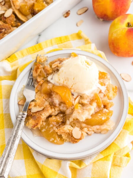 4 ingredient Peach Dump Cake on a plate with ice cream