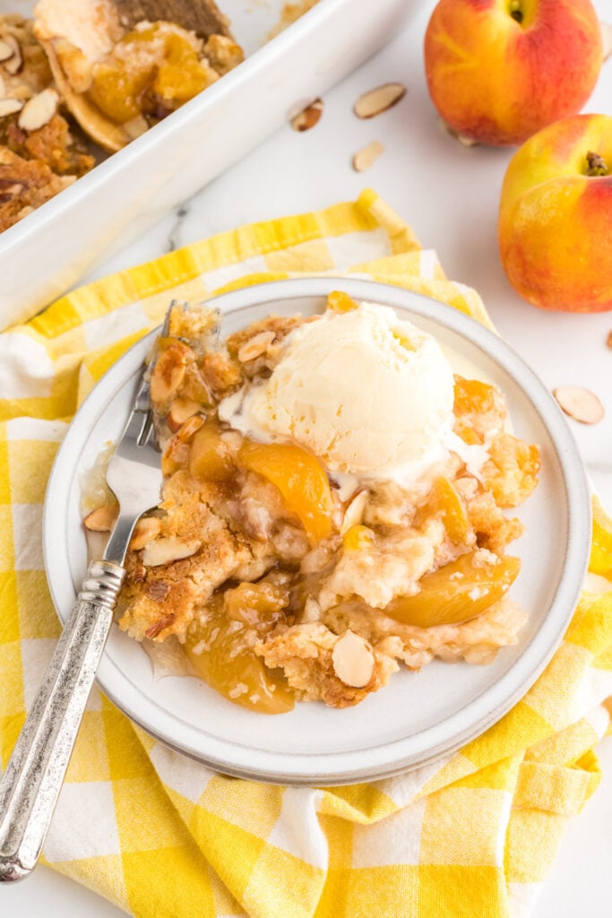 4 ingredient Peach Dump Cake on a plate with ice cream