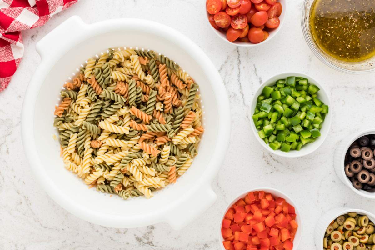 pasta in a bowl with small bowls of veggies