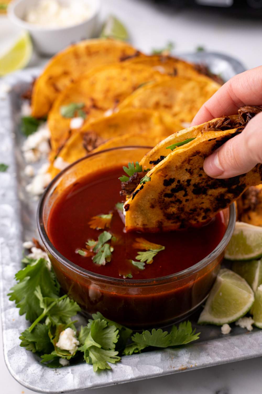 Slow Cooker Birria Taco being dipping in sauce