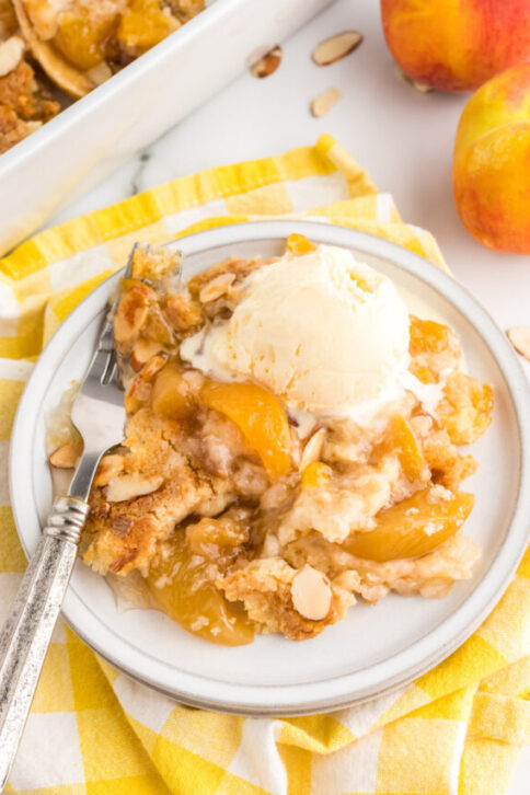4 ingredient Peach Dump Cake on a plate with ice cream