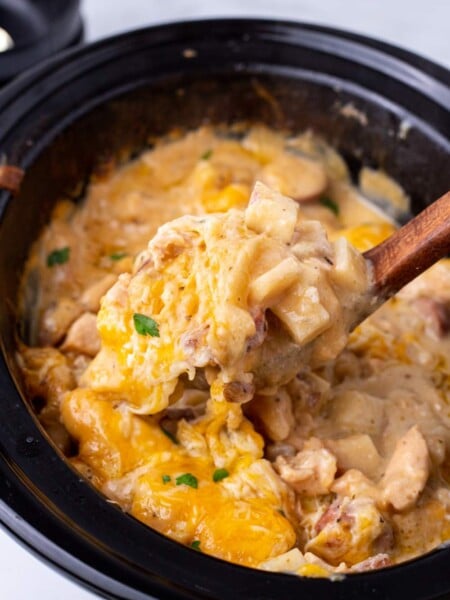 Crockpot Cheesy Chicken, Sausage, and Potato Casserole being scooped out of slow cooker