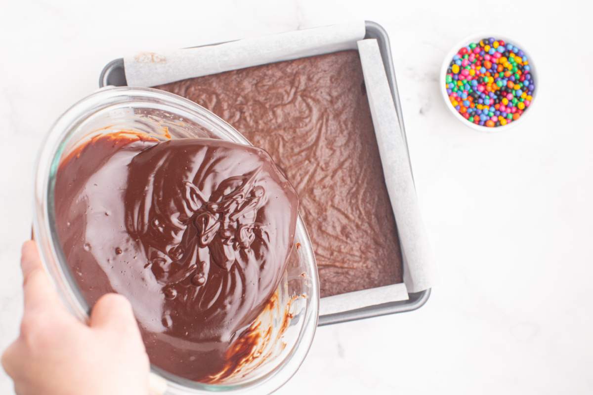 pouring chocolate topping over brownies