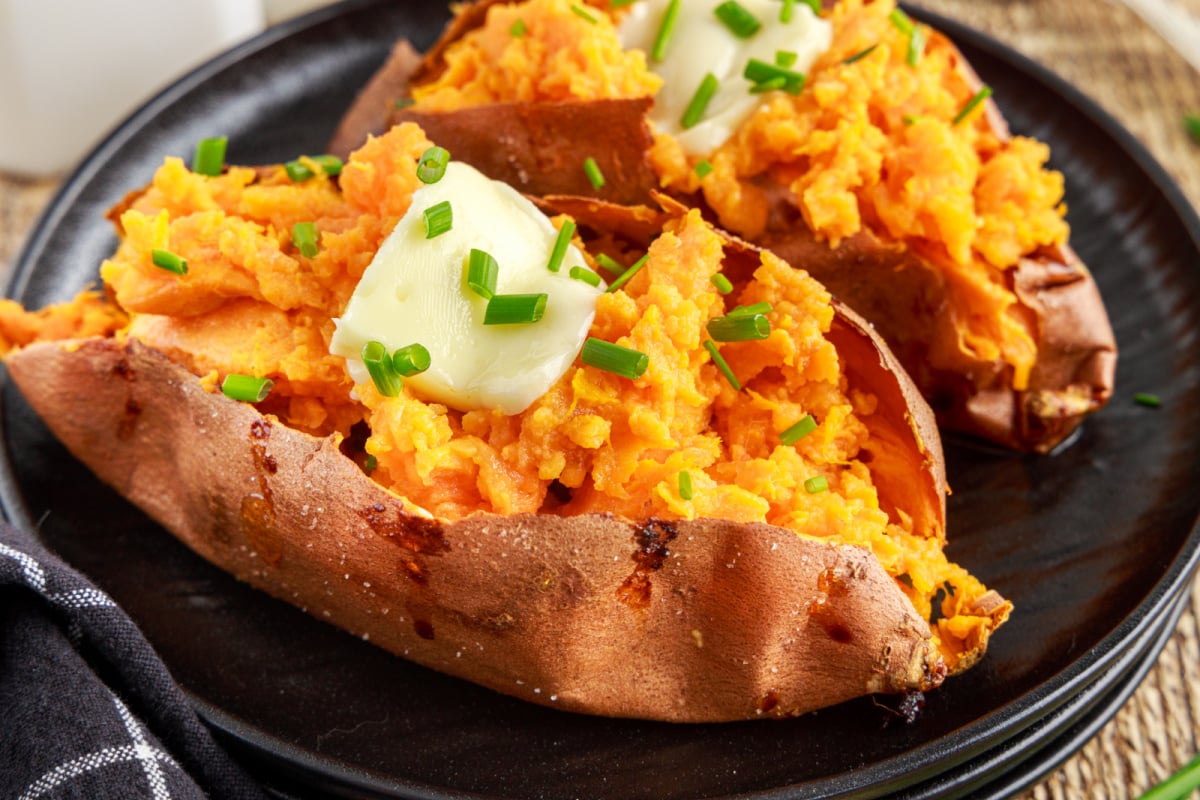 Baked Sweet Potatoes  on a plate with butter and chives