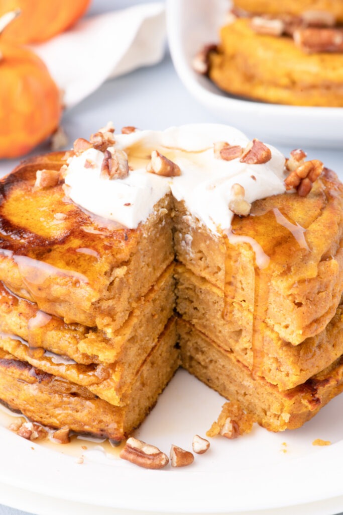 Stack of Fluffy Pumpkin Pancakes on a plate with a piece cut out