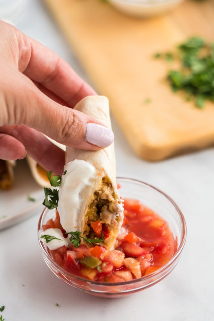 dipping Freezer Friendly Breakfast Taquitos in salsa