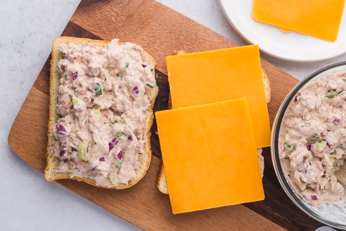 tuna salad on one slice of bread and sliced cheese on the other