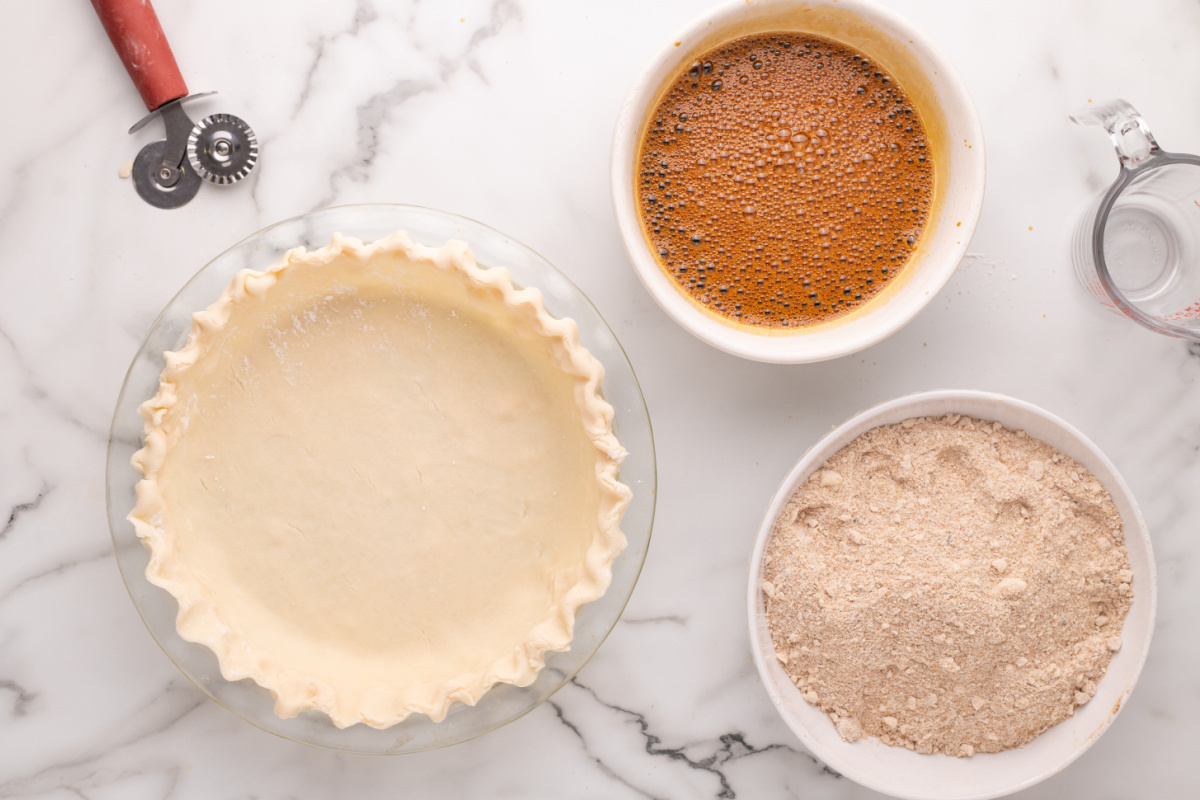 molasses mixture in a bowl, flour sugar mixture in a bowl and pie crust in pie pan