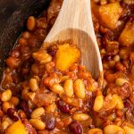 slow cooker hawaiian baked beans in slow cooker with wooden spoon