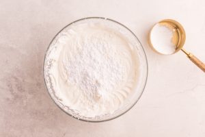 powdered sugar added to whipped cream bowl